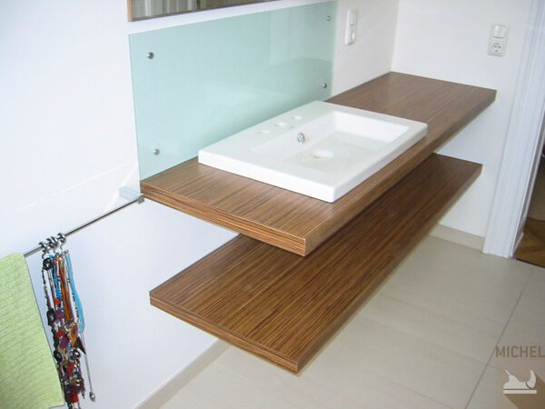 Modernes Badezimmer mit Waschbecken auf Holzplatte und Handtuchhalter an der Wand.