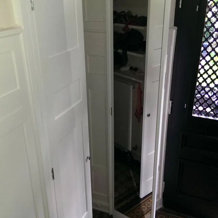 Eine weiße Schranktür mit Spiegel im Flur spiegelt den Eingangsbereich mit Musterglas wider.