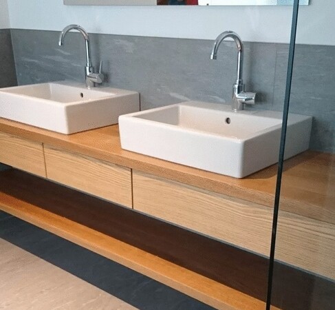 Modernes Badezimmer mit zwei eckigen Waschbecken auf Holz-Waschtisch und Wandarmaturen.