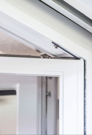 Ein weißer Insektenschutzrahmen mit Fliegengitter ist an einem Fenster montiert.